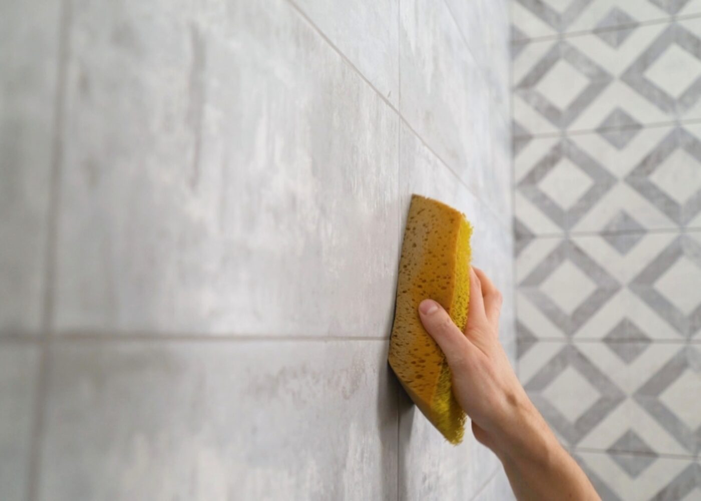 A,Man's,Hand,Wipes,A,Tiled,Wall,With,A,Sponge